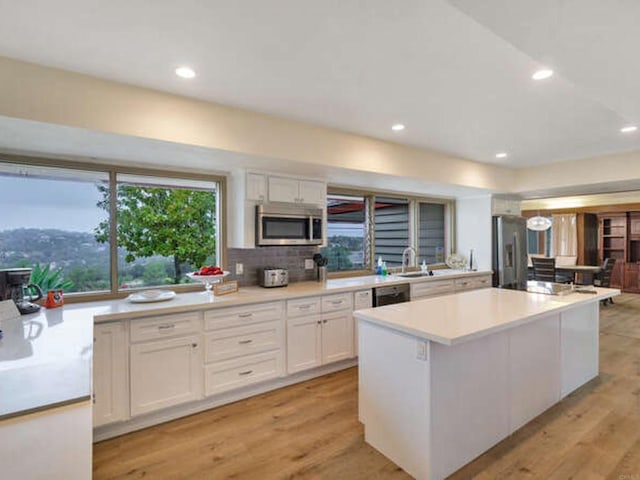 kitchen with recessed lighting, light countertops, a kitchen island, appliances with stainless steel finishes, and white cabinetry
