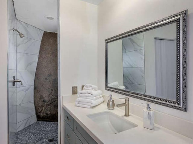 full bath with a tile shower and vanity
