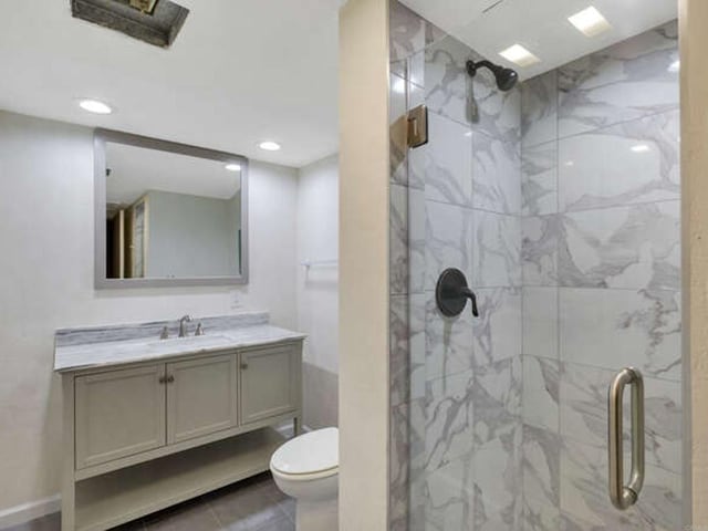 bathroom with toilet, vanity, a marble finish shower, and recessed lighting
