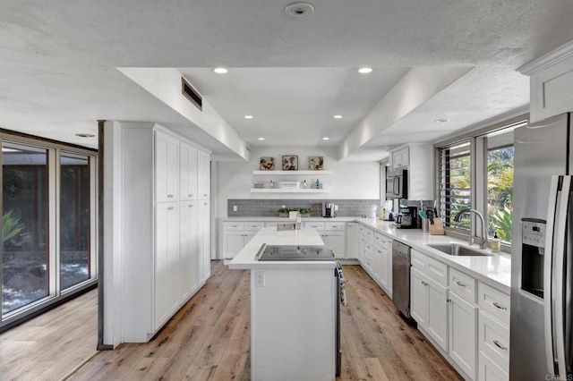 kitchen with stainless steel appliances, a sink, visible vents, backsplash, and a kitchen island