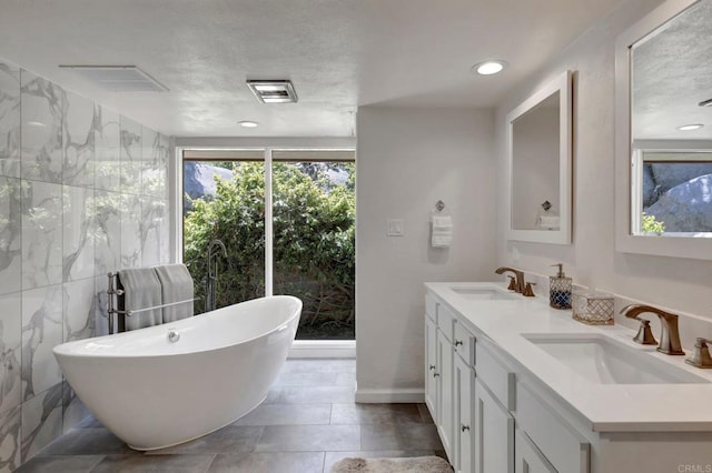 full bathroom with a freestanding bath, a sink, visible vents, and double vanity
