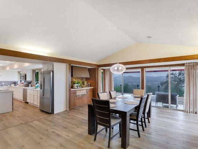 dining area with vaulted ceiling and light wood finished floors