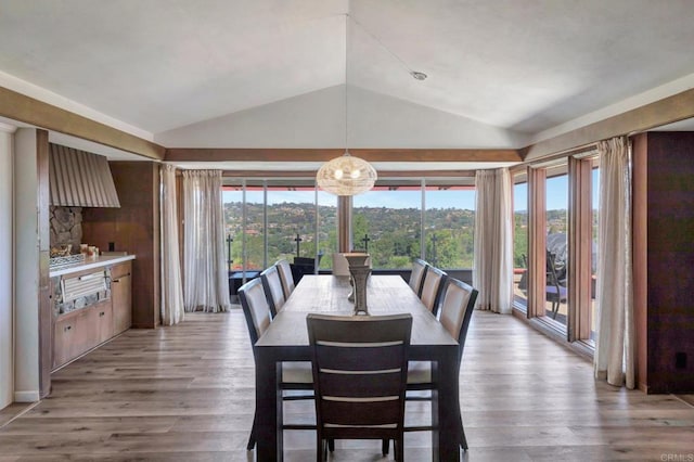dining room featuring a chandelier, vaulted ceiling, and light wood-type flooring