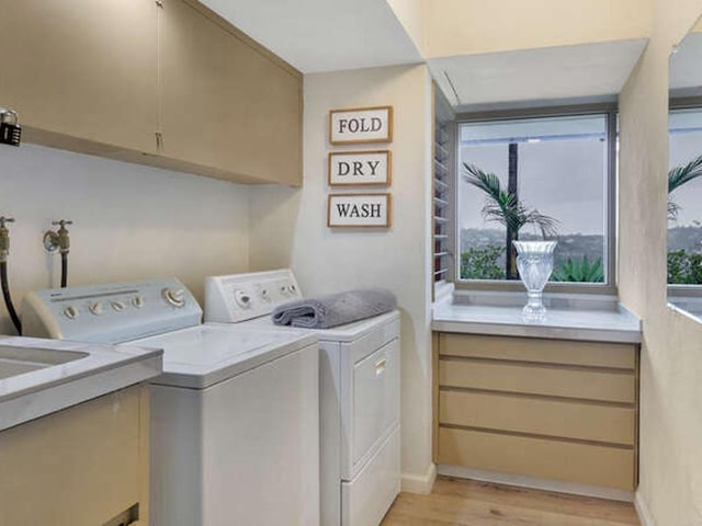 washroom with light wood-style flooring, baseboards, washer and clothes dryer, and cabinet space