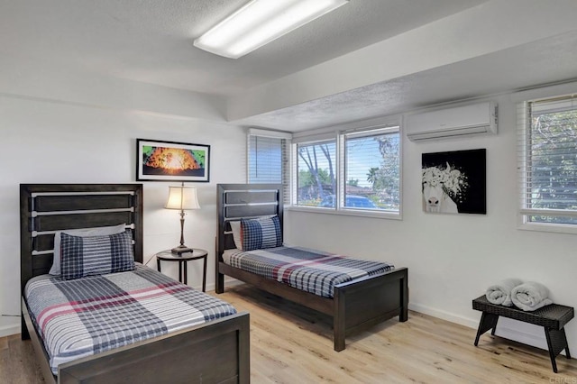 bedroom featuring an AC wall unit, baseboards, and wood finished floors