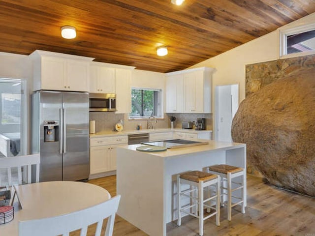 kitchen featuring a kitchen island, wood ceiling, decorative backsplash, appliances with stainless steel finishes, and white cabinetry