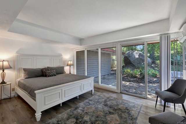 bedroom featuring wood finished floors, access to exterior, and multiple windows