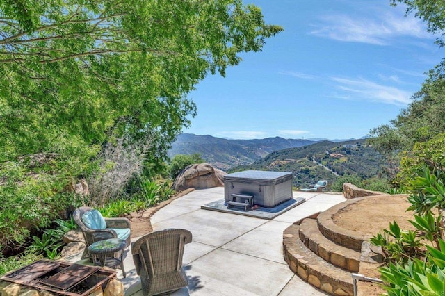 view of patio with a mountain view and a hot tub