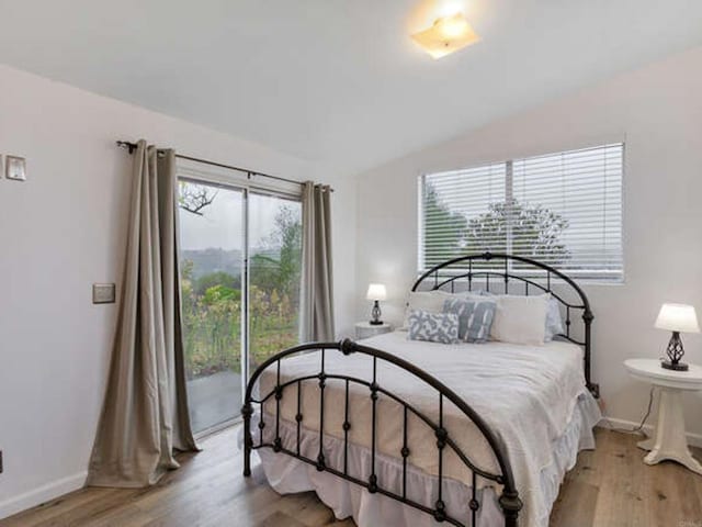 bedroom with light wood-style floors, lofted ceiling, access to exterior, and baseboards