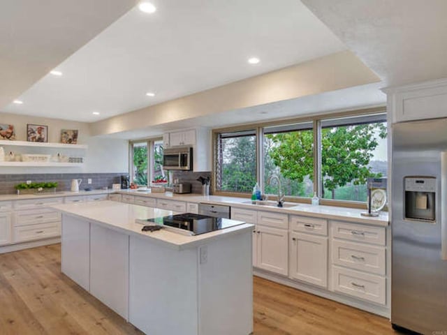 kitchen featuring a center island, stainless steel appliances, light countertops, and a sink