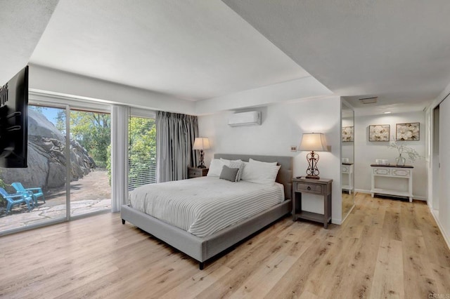 bedroom with a wall mounted air conditioner, baseboards, access to outside, and light wood-type flooring