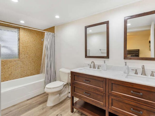 bathroom featuring recessed lighting, double vanity, wood finished floors, toilet, and a sink