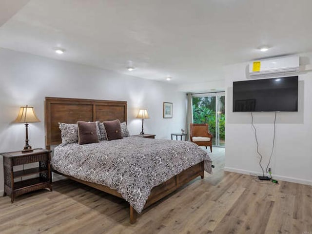 bedroom featuring a wall mounted AC, light wood-type flooring, baseboards, access to exterior, and recessed lighting