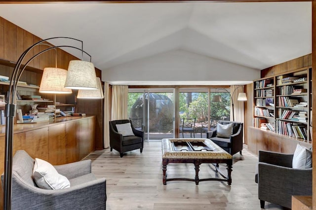 sitting room featuring wooden walls, vaulted ceiling, and light wood-style flooring