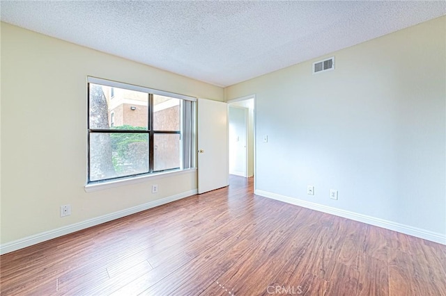 empty room featuring wood-type flooring and a textured ceiling