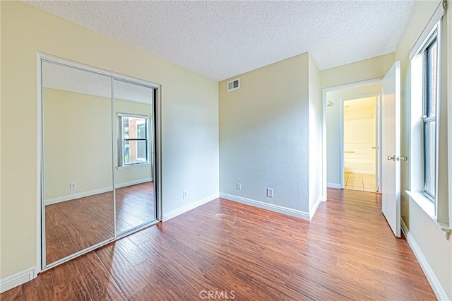 unfurnished bedroom featuring hardwood / wood-style flooring, a textured ceiling, and a closet