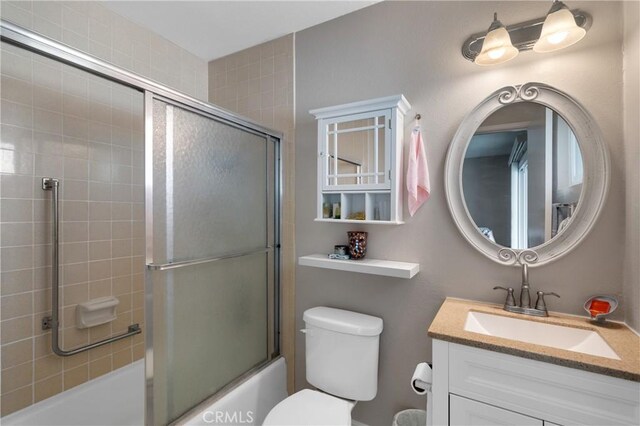 full bathroom featuring vanity, bath / shower combo with glass door, and toilet