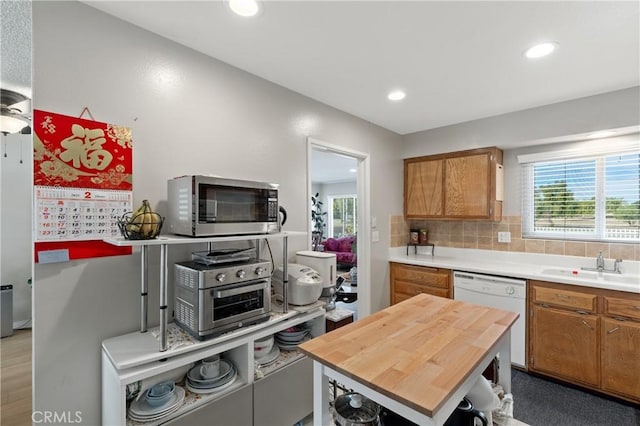 kitchen featuring sink, a center island, white dishwasher, tasteful backsplash, and wood counters