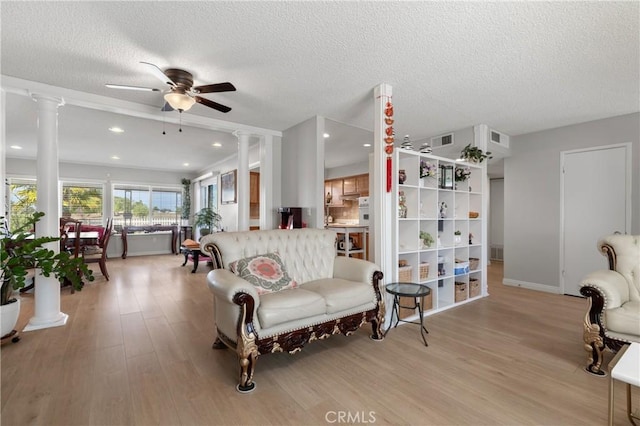 living room featuring decorative columns, ceiling fan, and light hardwood / wood-style floors