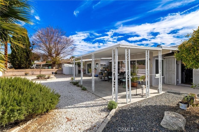 rear view of property with a patio and a storage unit