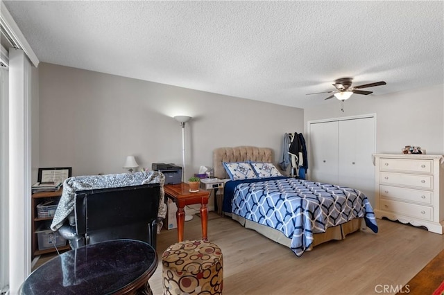 bedroom with hardwood / wood-style floors, a textured ceiling, ceiling fan, and a closet