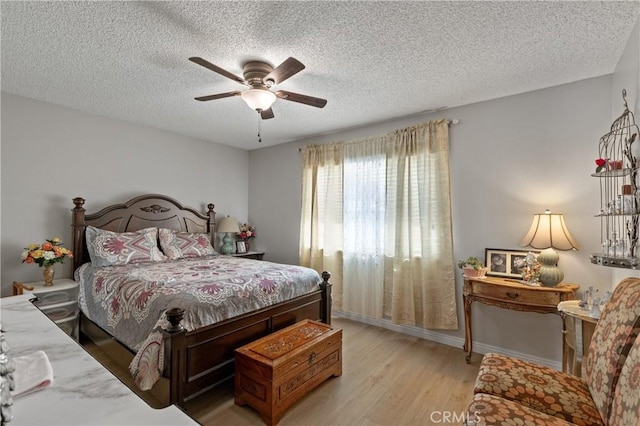 bedroom with a textured ceiling, light hardwood / wood-style floors, and ceiling fan