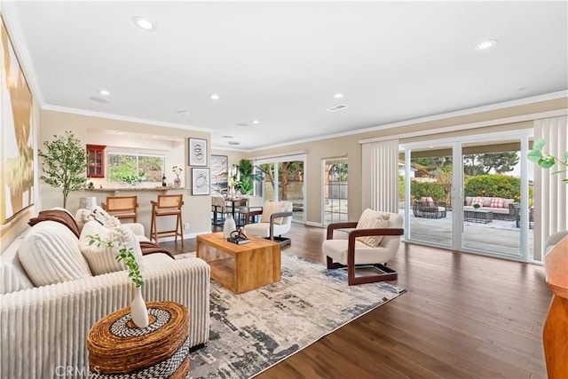 living room with wood-type flooring, a wealth of natural light, and crown molding