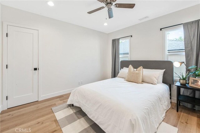 bedroom featuring multiple windows, light hardwood / wood-style floors, and ceiling fan