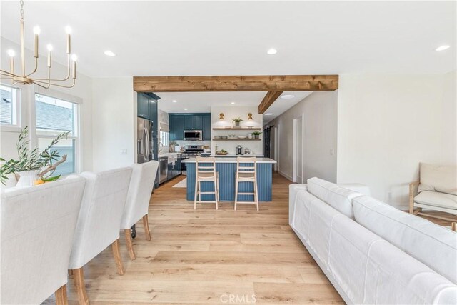 kitchen featuring pendant lighting, blue cabinetry, stainless steel appliances, a kitchen breakfast bar, and light hardwood / wood-style floors