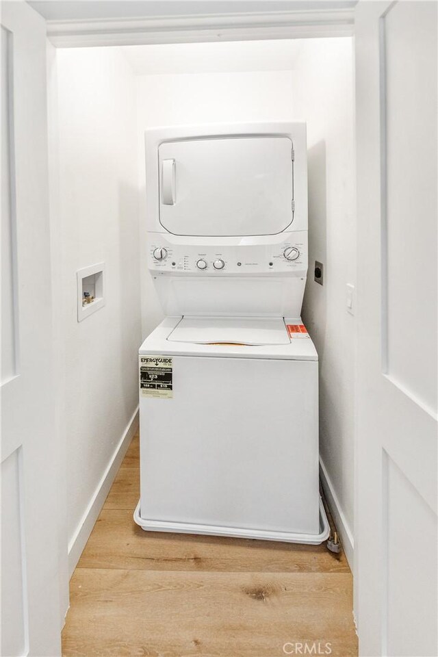 washroom featuring stacked washer and clothes dryer and light wood-type flooring