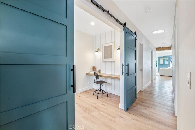 corridor featuring a barn door and light wood-type flooring