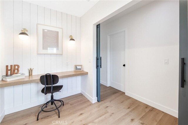 home office with built in desk and light hardwood / wood-style floors