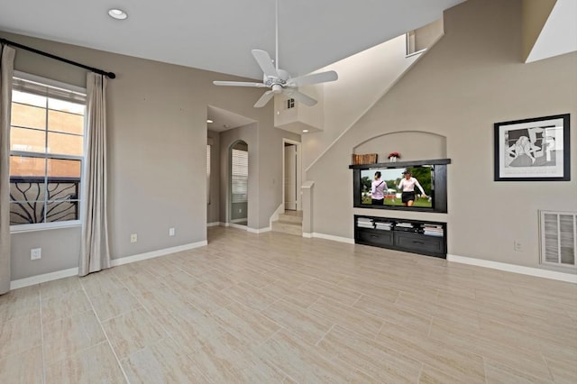 unfurnished living room with ceiling fan and a high ceiling