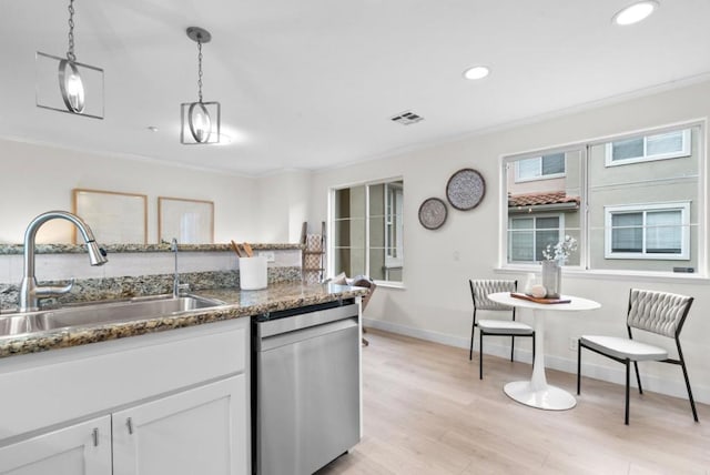 kitchen featuring sink, dishwasher, white cabinetry, decorative light fixtures, and dark stone counters