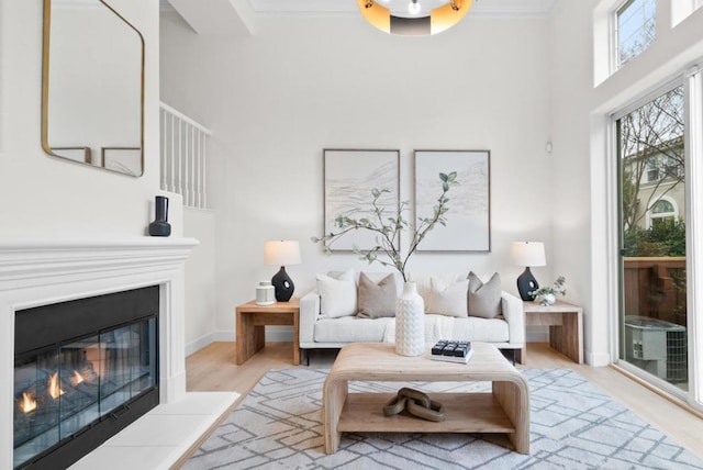 living room with ornamental molding, a towering ceiling, and light hardwood / wood-style floors