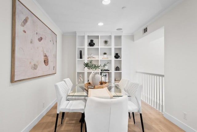 dining space featuring ornamental molding and light hardwood / wood-style flooring