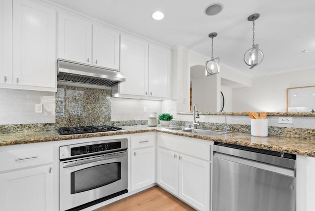 kitchen with sink, white cabinets, dark stone counters, hanging light fixtures, and stainless steel appliances