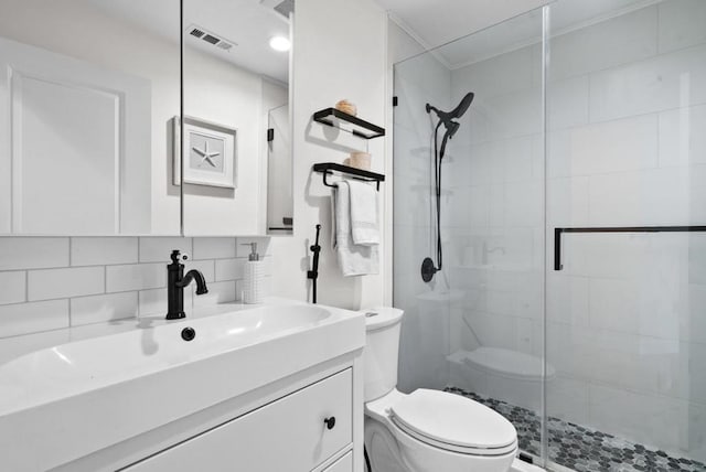 bathroom with a shower with door, vanity, toilet, and decorative backsplash