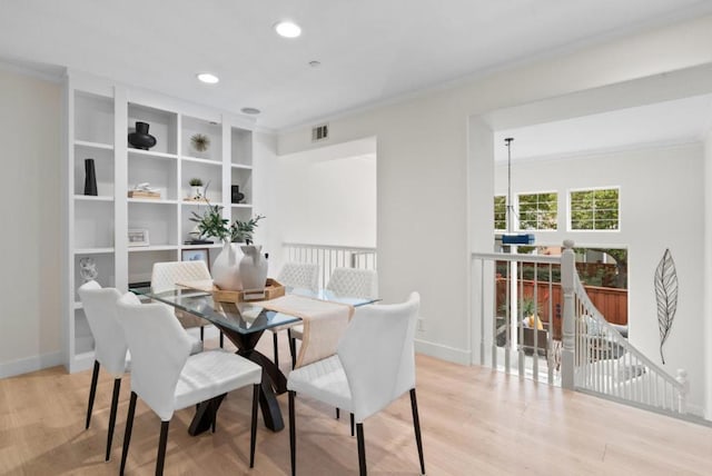 dining space featuring ornamental molding and light hardwood / wood-style floors