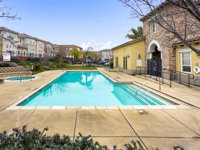 view of swimming pool featuring a hot tub and a patio