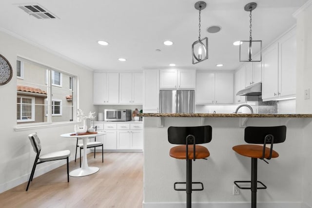 kitchen featuring stainless steel appliances, dark stone countertops, white cabinets, and light hardwood / wood-style flooring