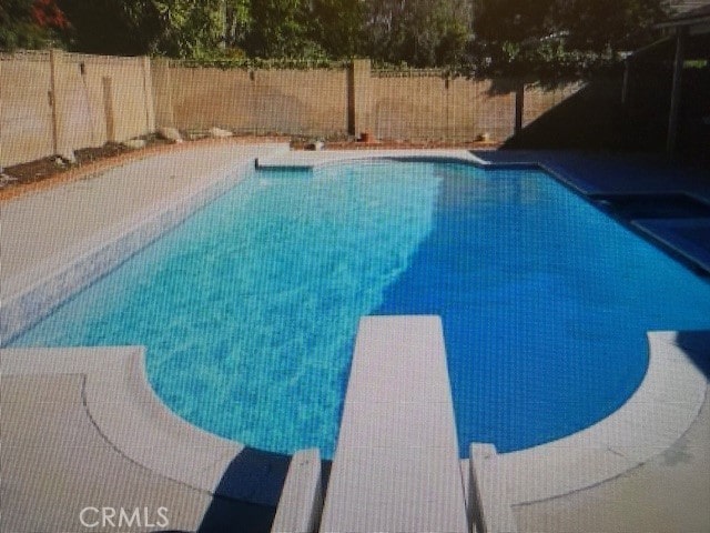 view of swimming pool featuring a diving board