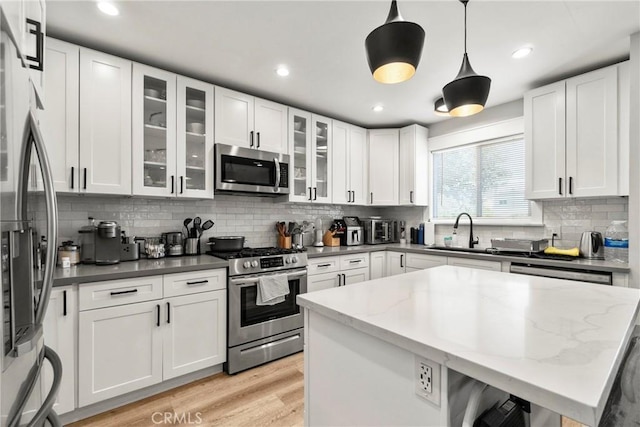 kitchen with pendant lighting, sink, appliances with stainless steel finishes, dark stone countertops, and white cabinets