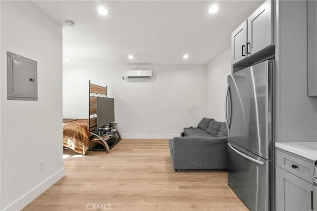 kitchen with stainless steel refrigerator, a wall mounted air conditioner, electric panel, and gray cabinetry