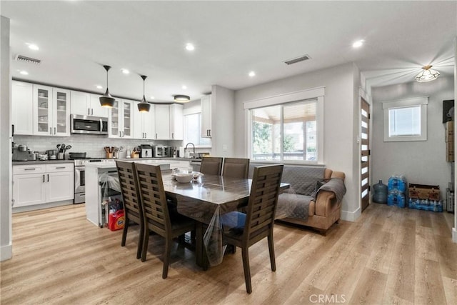 dining area with sink, light hardwood / wood-style flooring, and a healthy amount of sunlight