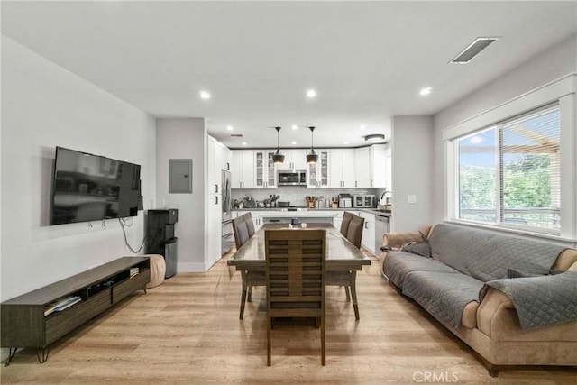 dining room featuring electric panel and light hardwood / wood-style flooring