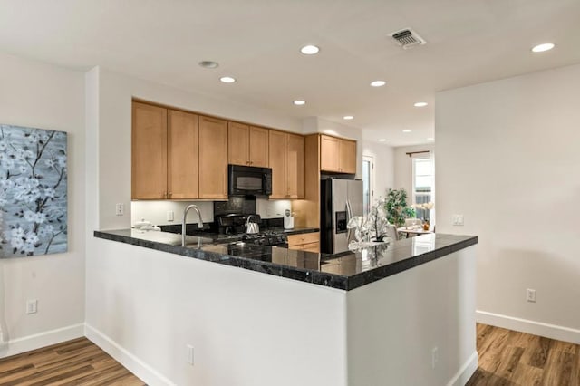 kitchen with kitchen peninsula, sink, light hardwood / wood-style flooring, and black appliances