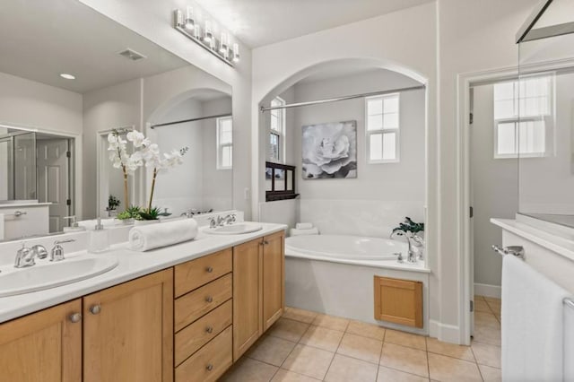 bathroom with tile patterned flooring, vanity, a tub, and a wealth of natural light