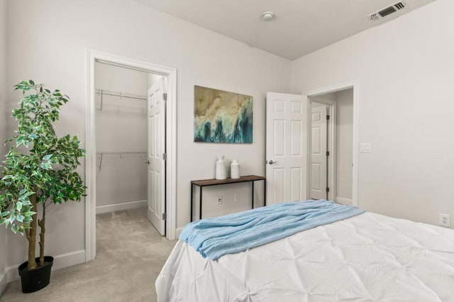 bedroom with light colored carpet, a spacious closet, and a closet