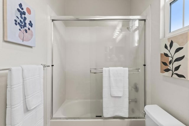 bathroom with toilet and combined bath / shower with glass door